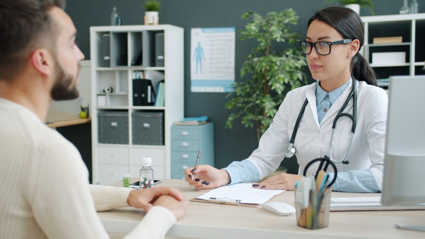 Médica conversando com um paciente durante consulta de avaliação no consultório